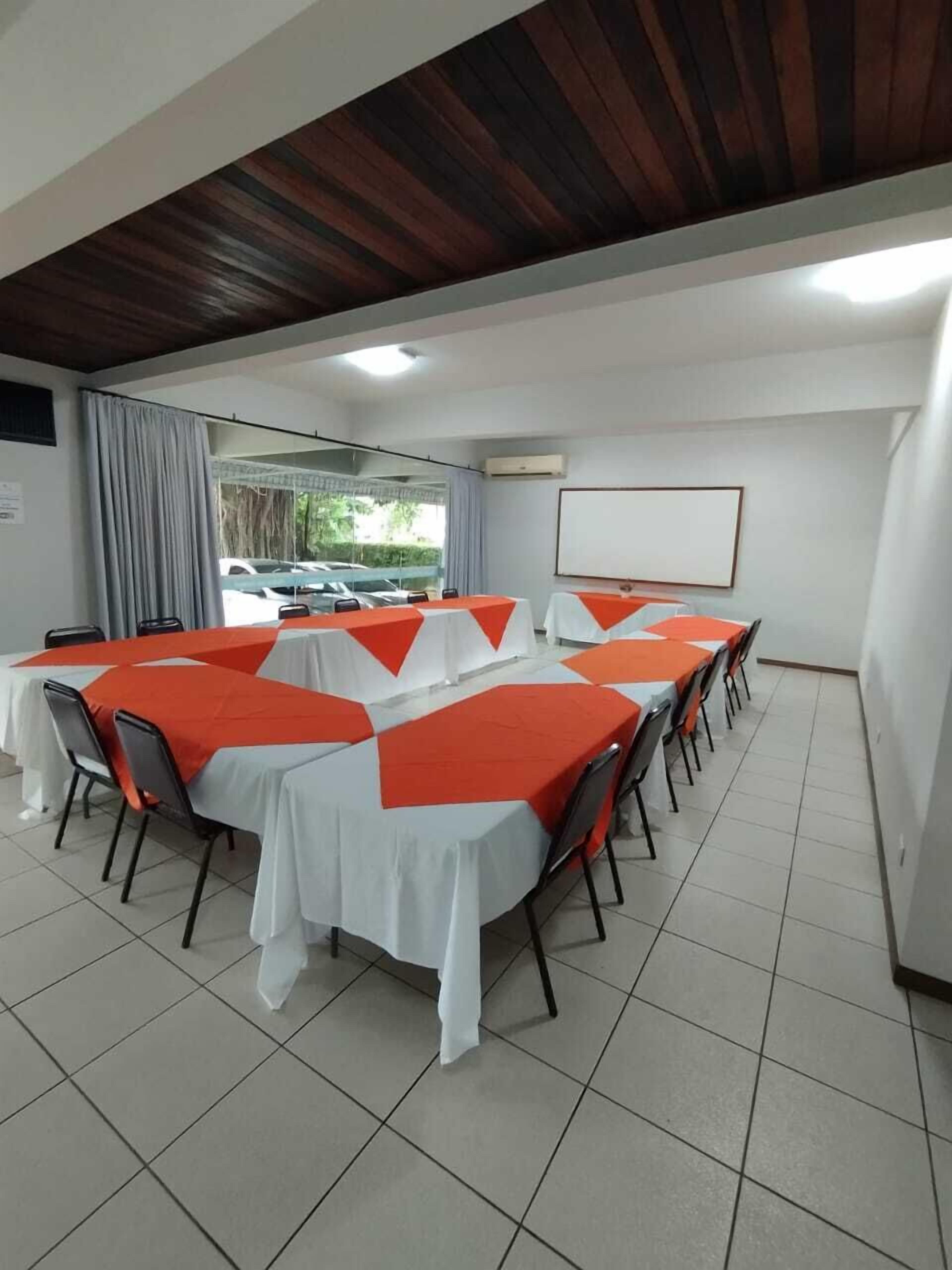 A conference room with tables set for meetings, a whiteboard, and a projector screen.