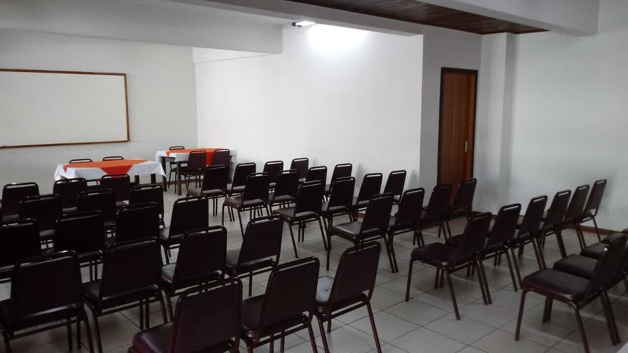 A conference room with rows of chairs and tables, a whiteboard, and a door.