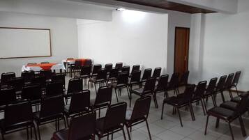 A conference room with rows of chairs and tables, a whiteboard, and a door.