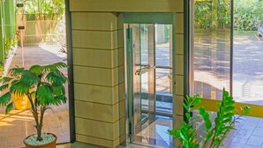 A modern entrance with a glass door, potted plants, and a view of the street outside. - Harbor Inn Jaraguá (Jaragua do Sul)