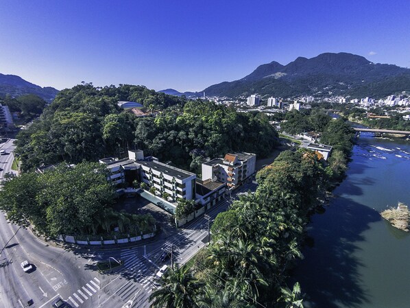 An aerial view of a city with a river, buildings, and mountains in the background.