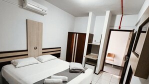 A modern hotel room with a large bed, a wardrobe, a TV, and a bathroom visible through an open door. - Harbor Inn Jaraguá (Jaragua do Sul)