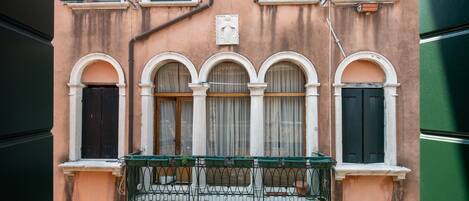 A building with arched windows, a balcony with a metal railing, and a door.