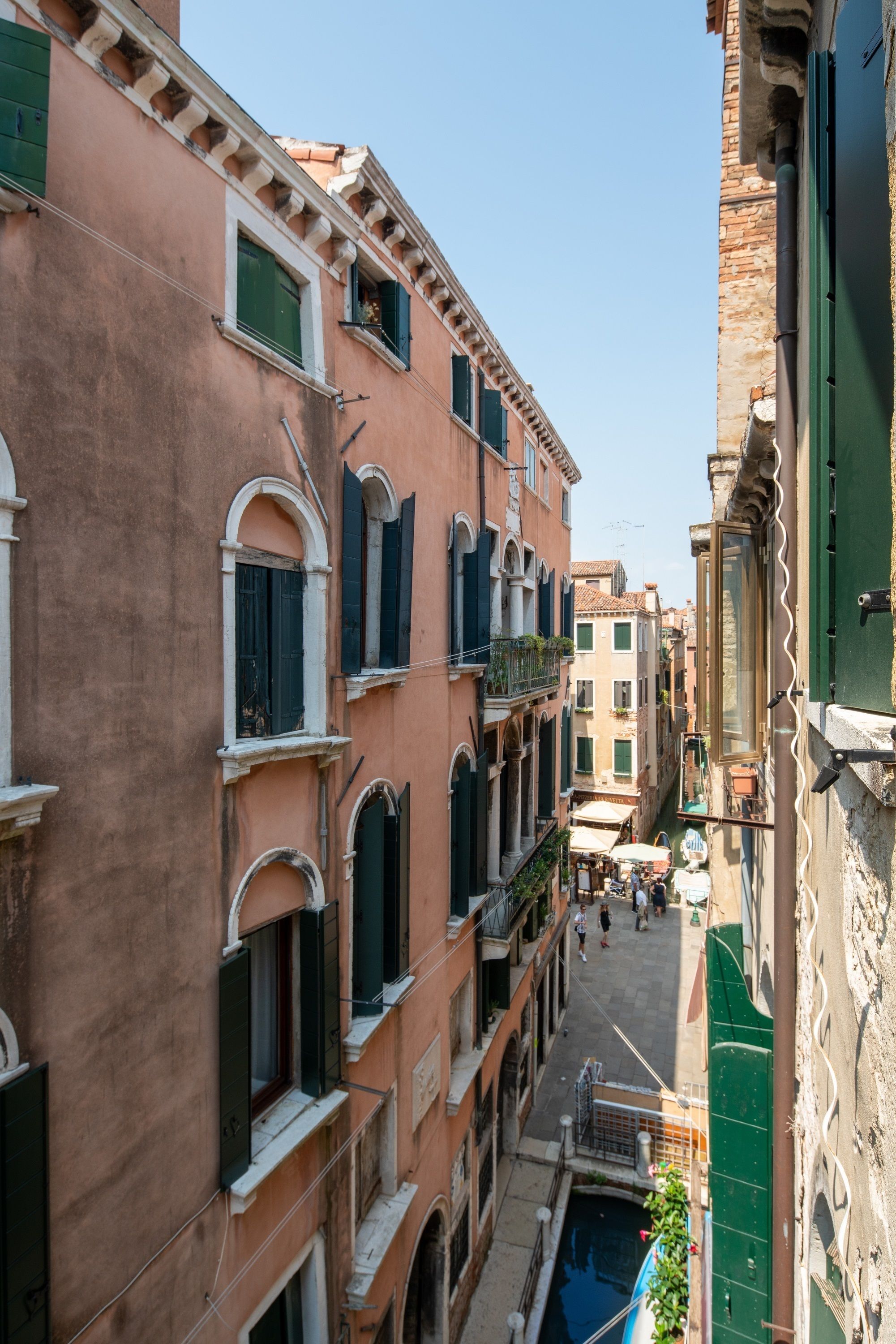 Un'angusta calle veneziana con edifici a più piani, balconi e un canale.