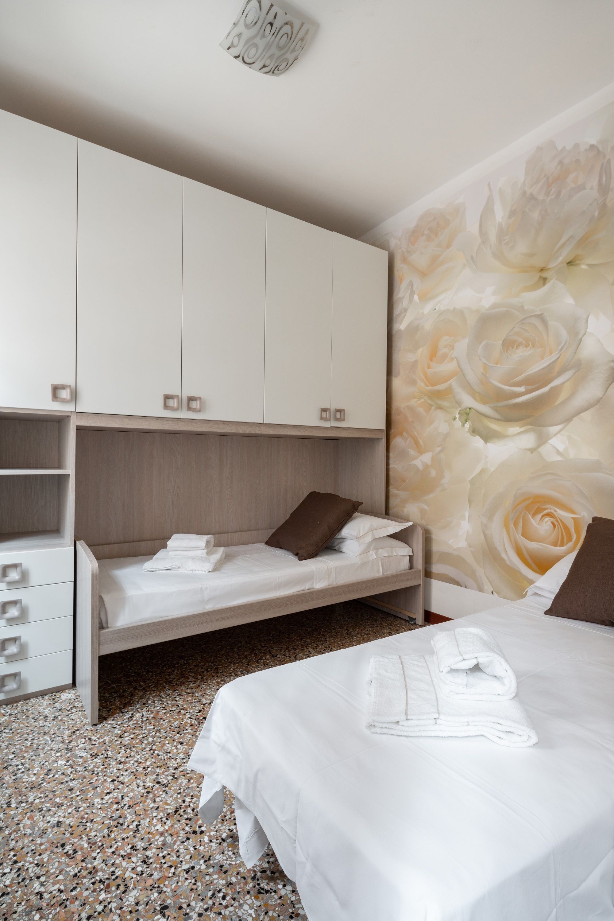 Een hotelkamer met een bed, een kledingkast en bloemenbehang.