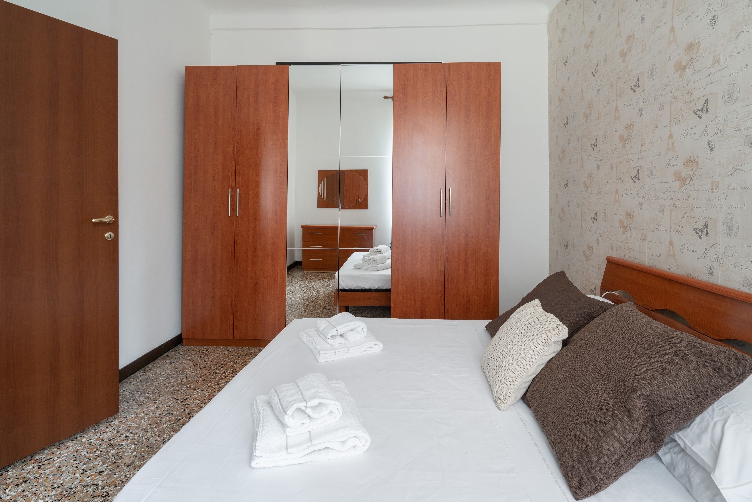 Quarto de hotel com uma cama, um guarda-roupa e um espelho.