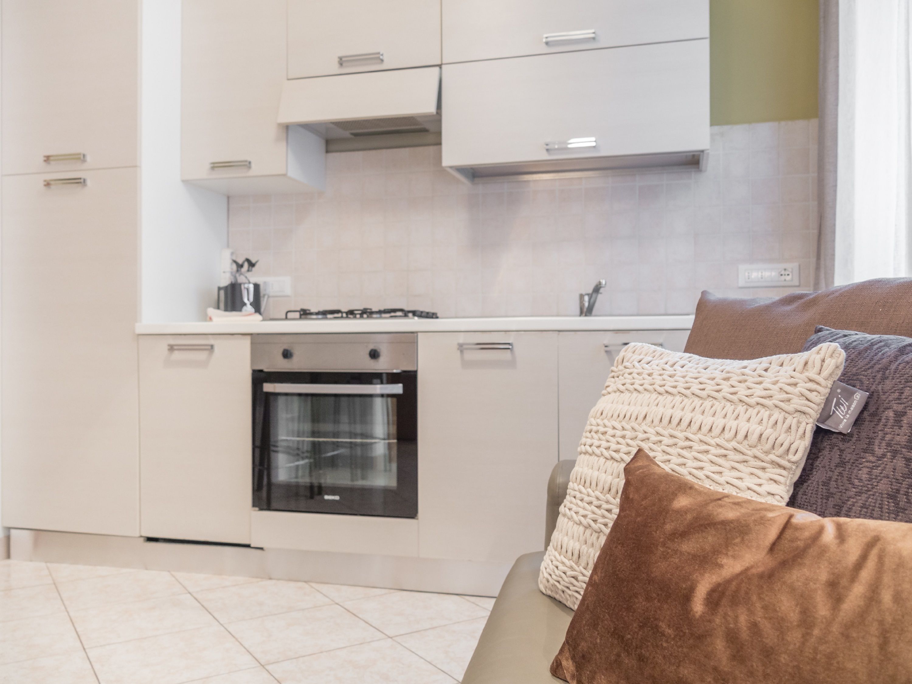 A modern kitchen with white cabinets, a built-in oven, and a gas stove.