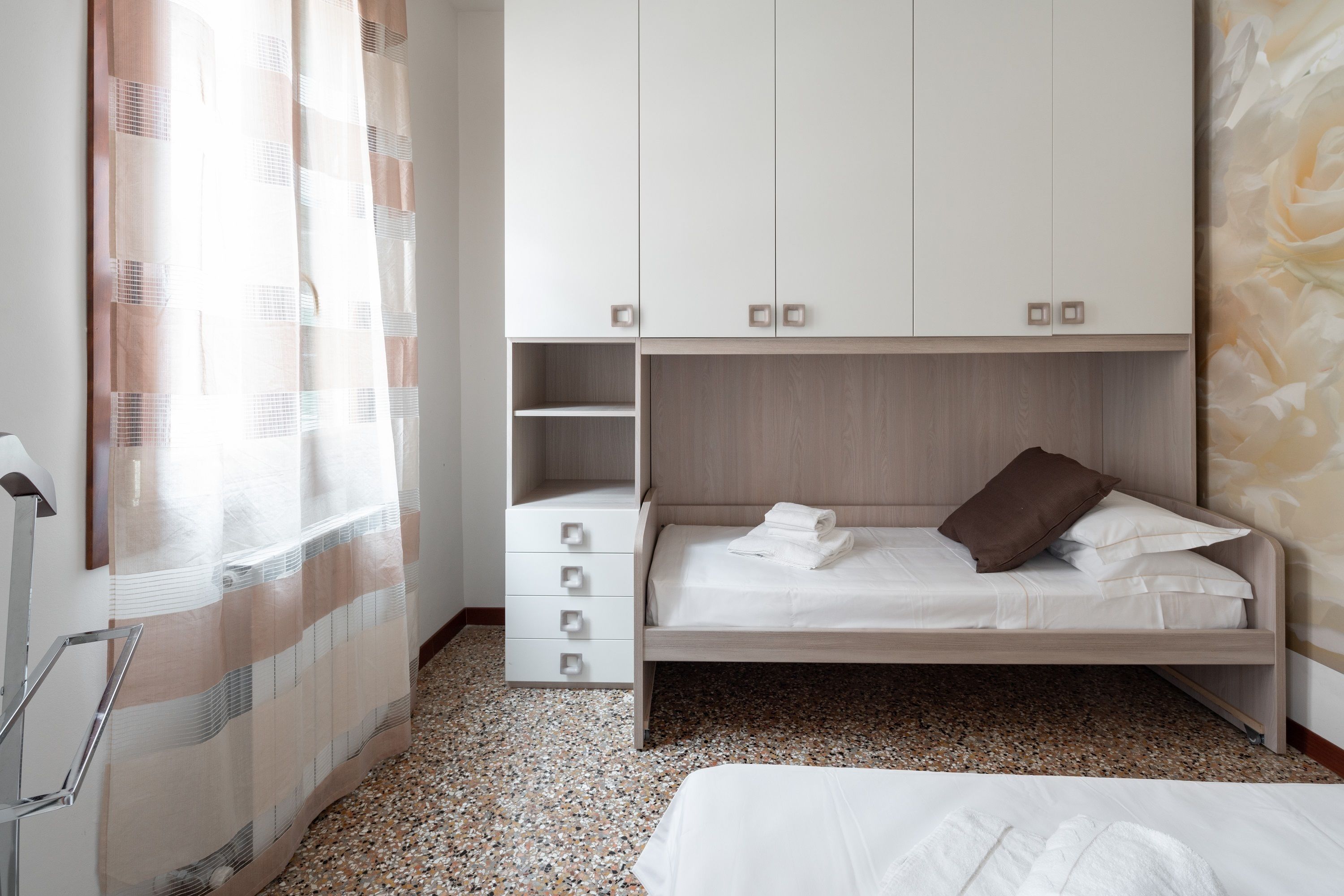 A bedroom with a bunk bed, a wardrobe, a shower area, and a small bathroom.