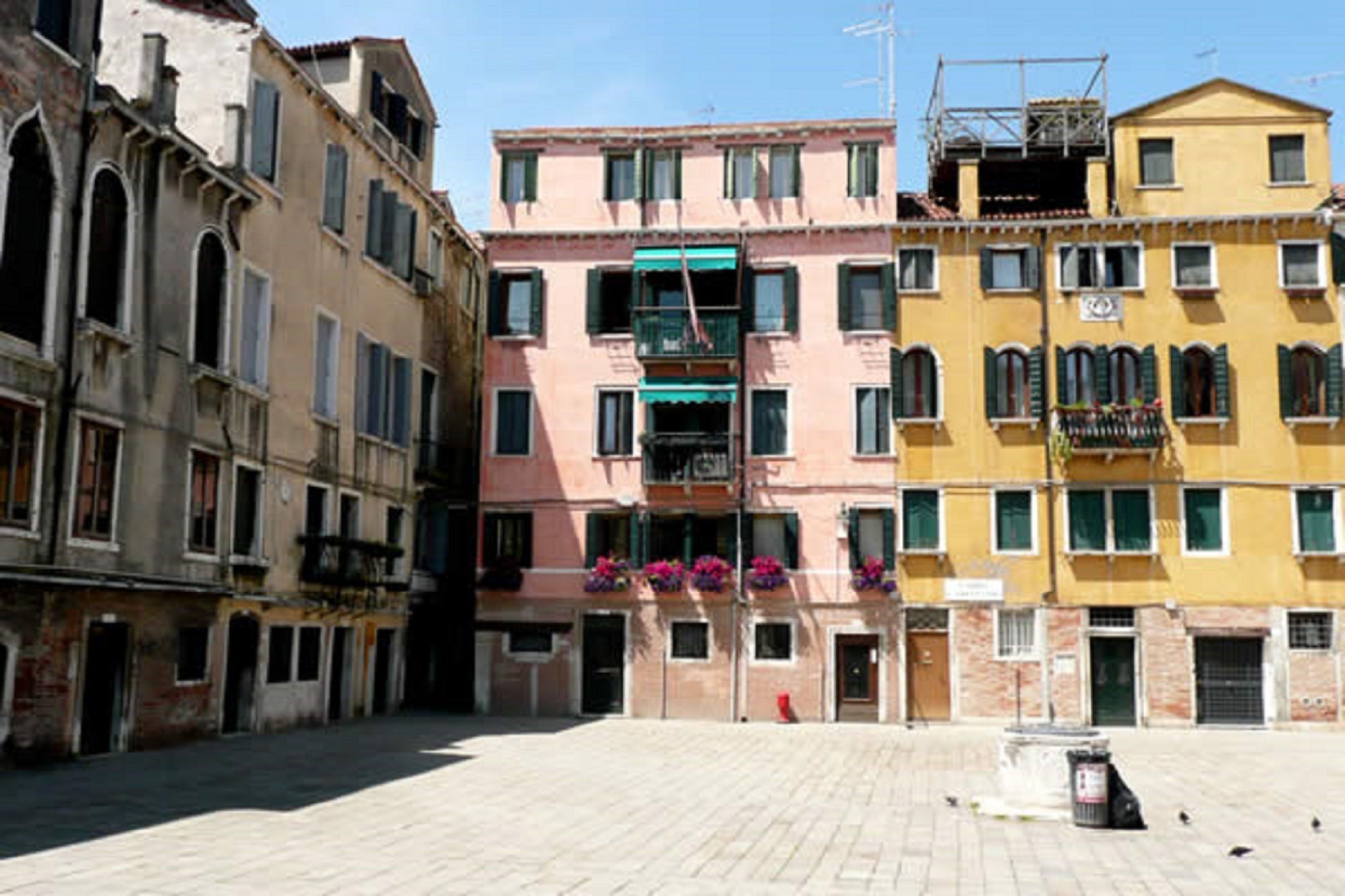 Uma praça histórica com edifícios de arquitetura tradicional, incluindo janelas em arco e sacadas.