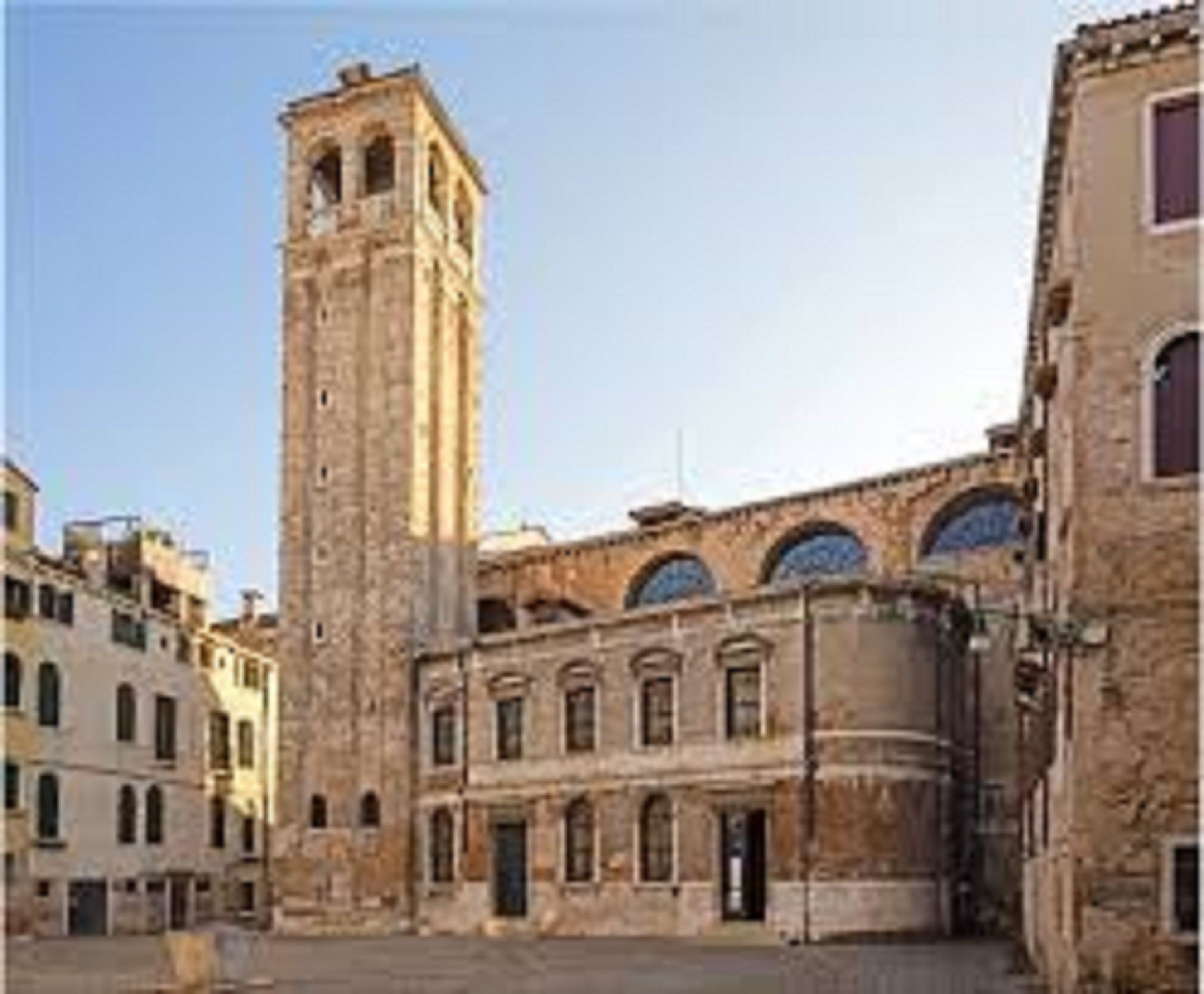 Un edificio histórico con una torre destacada y ventanas de arco.