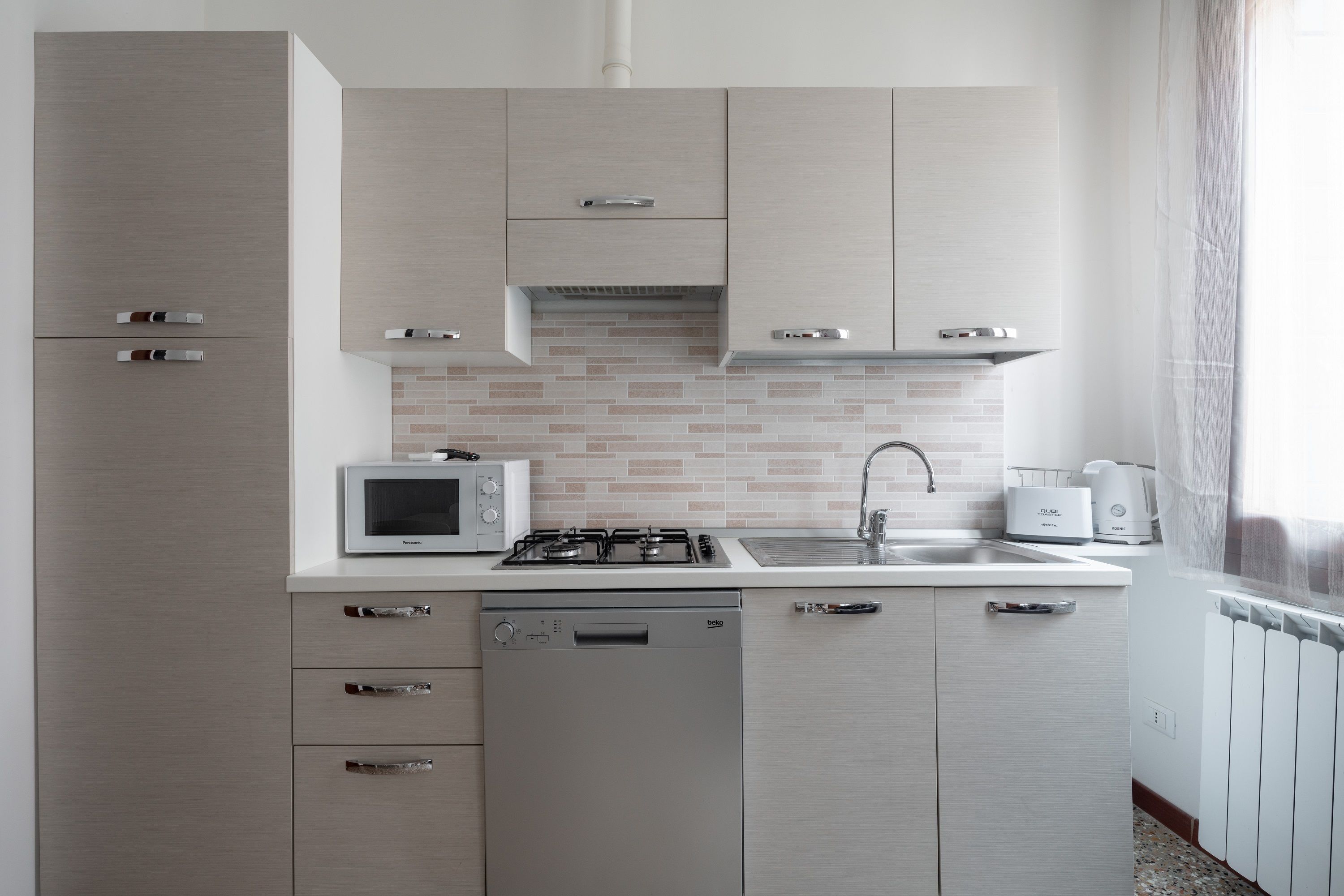 A modern kitchen with a dishwasher, microwave, stove, and sink.