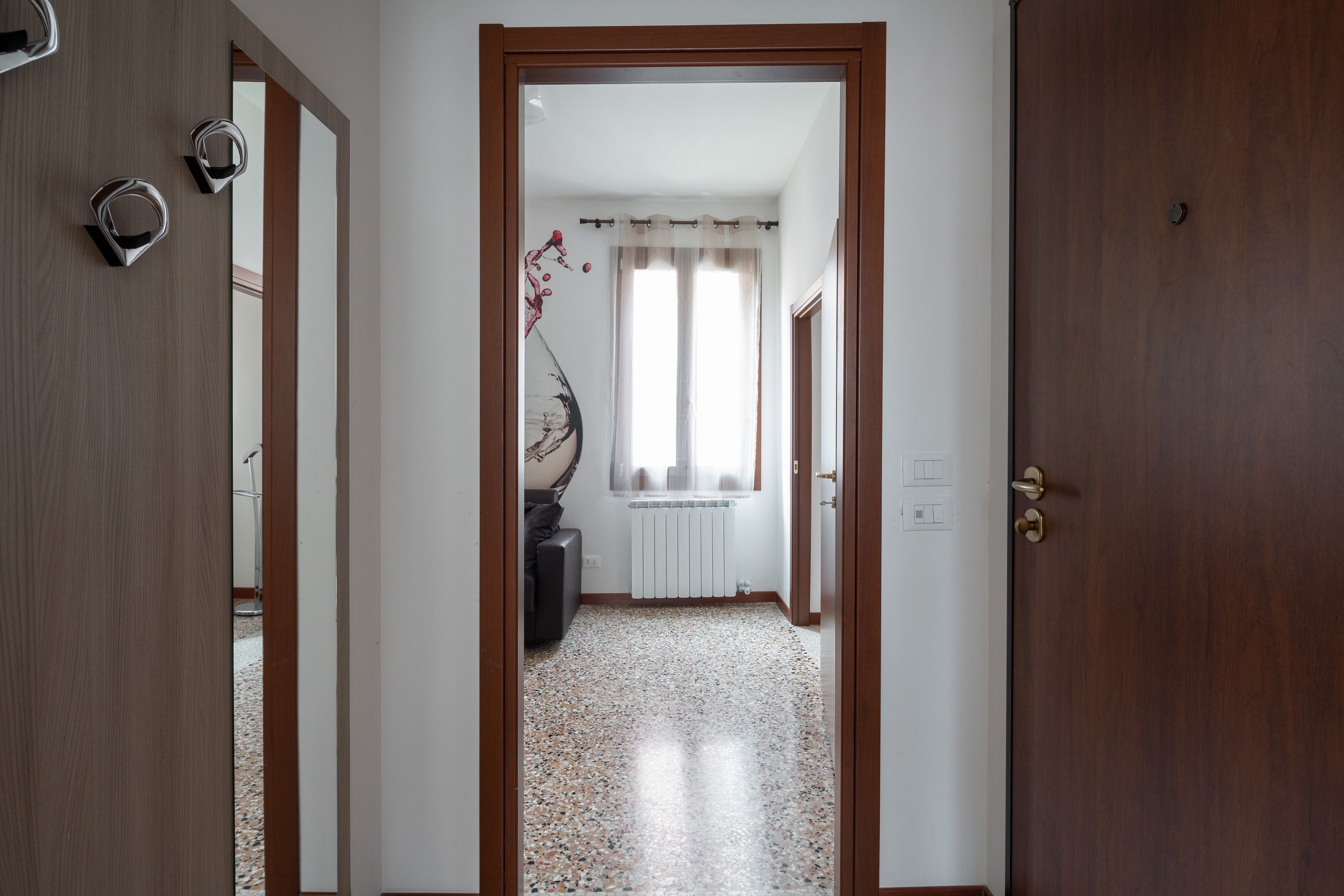 A hallway with a wooden door, a radiator, and a window with curtains.