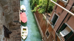 A narrow canal with boats, a building with a balcony, and a rope. - San Polo Canal View Apartments by Wonderful Italy (Venice)