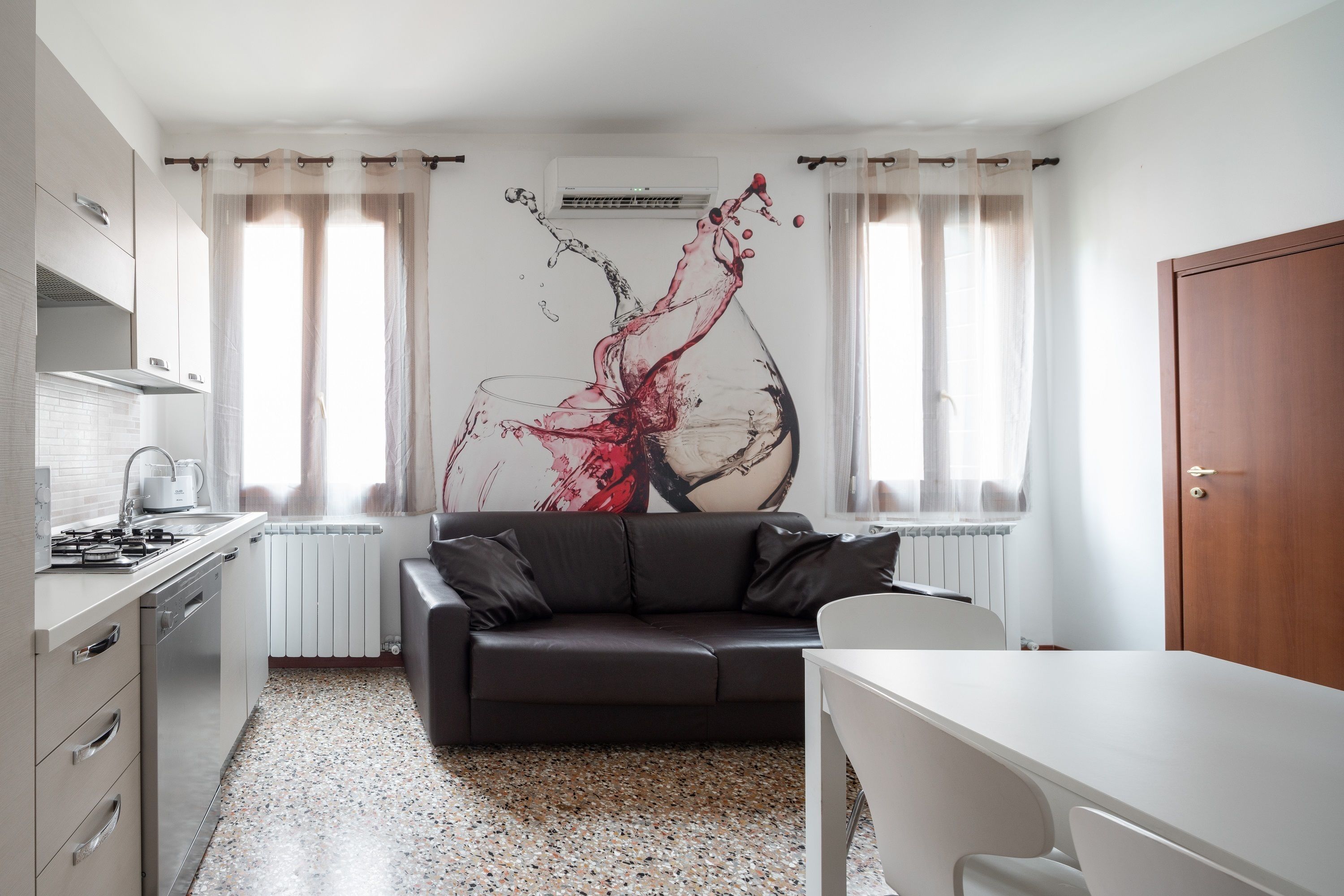 Una cocina moderna con zona de comedor, sofá y un cuadro abstracto grande en la pared.