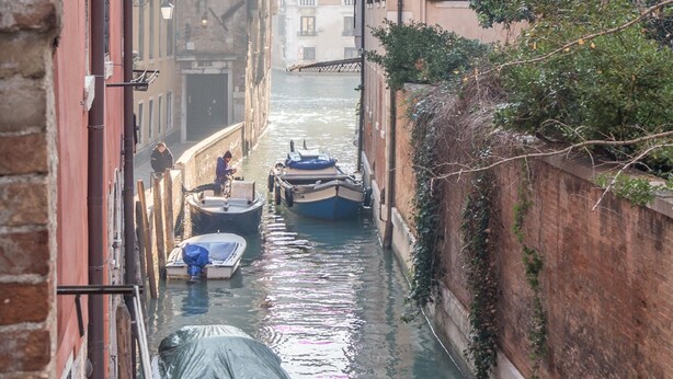 A narrow canal flanked by historic buildings with boats docked along the water. - San Polo Canal View Apartments by Wonderful Italy (Venice)