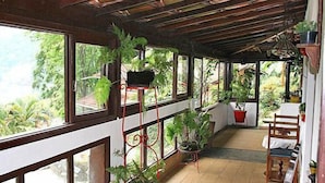 En inglasad veranda med flera fönster, krukväxter och en trästol.