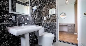 A bathroom with a white sink, a toilet, and a shower area. There is a mirror above the sink and a towel rack on the wall. - Mirvill Pension (Seogwipo)