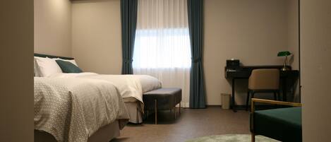 Habitación de hotel con cama, escritorio, silla y alfombra redonda pequeña.