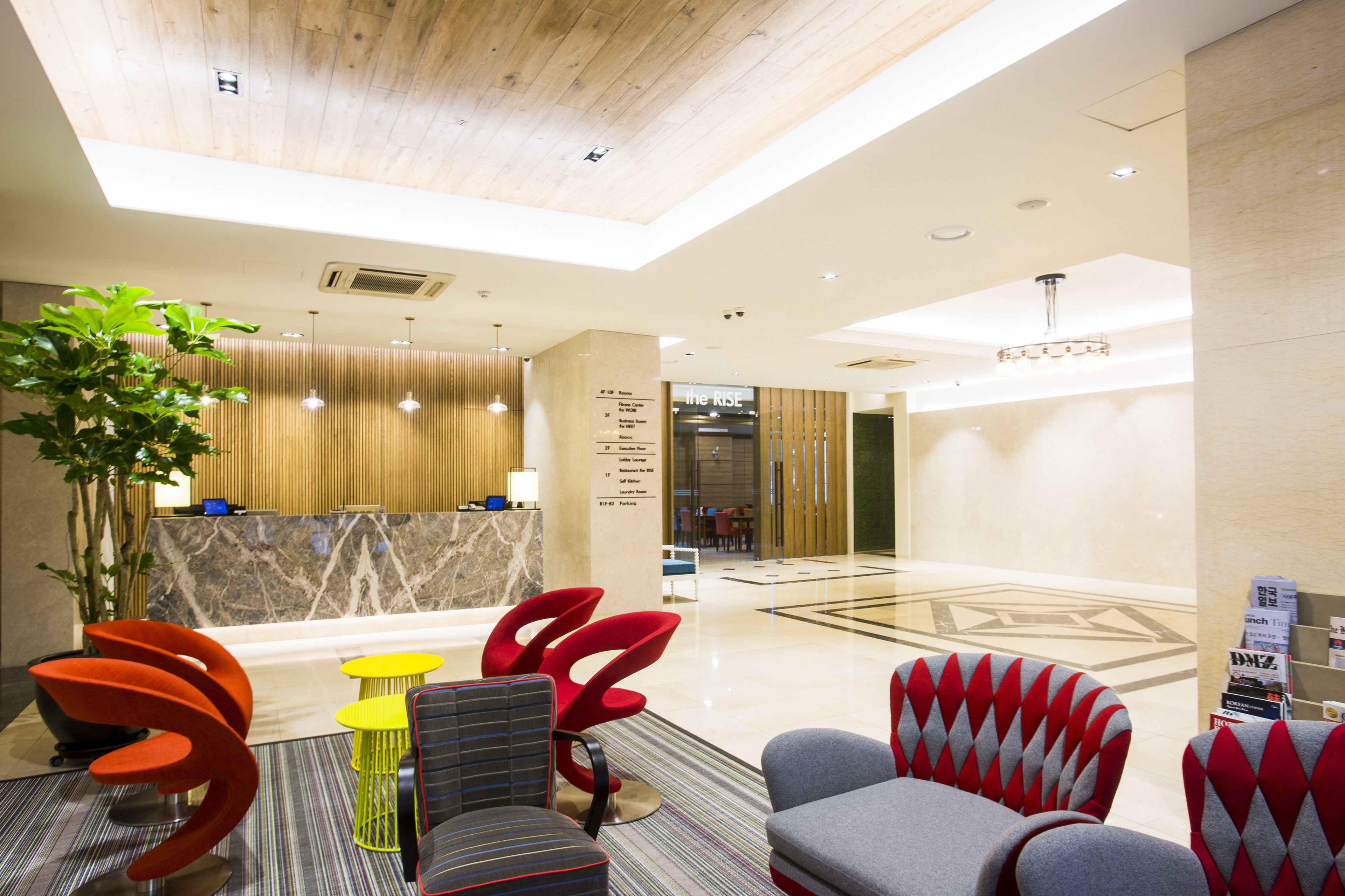 A modern lobby with a reception desk, seating area, and a large plant.