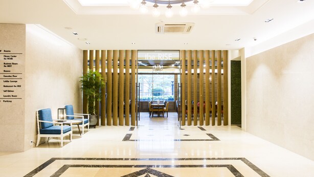 A hotel lobby with a polished marble floor, a reception desk, and a view through a glass door. - Polaris Hotel (Bucheon)