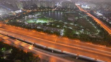 Vista aérea de un paisaje urbano nocturno con un lago destacado, edificios circundantes y una autopista de varios niveles.