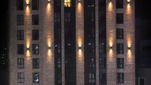 Un hotel con fachada de ladrillo, varias ventanas y señalización iluminada.