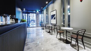 Un moderno vestíbulo de hotel con piso de mármol, una recepción y varias mesas y sillas.
