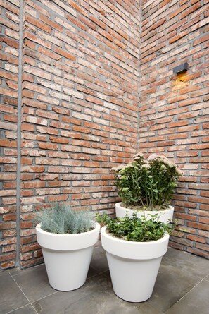 A corner with a brick wall and two white planters with plants. - GM JS Boutique Hotel (Gwangmyeong)