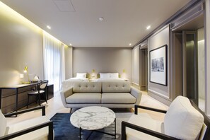 A modern hotel room with a sofa, a desk, a chair, a round table, and a bed. - GM JS Boutique Hotel (Gwangmyeong)