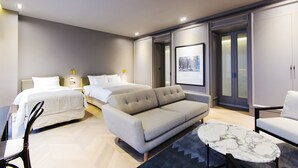 Una habitación de hotel moderna con una cama grande, un sofá, una mesita y un armario.
