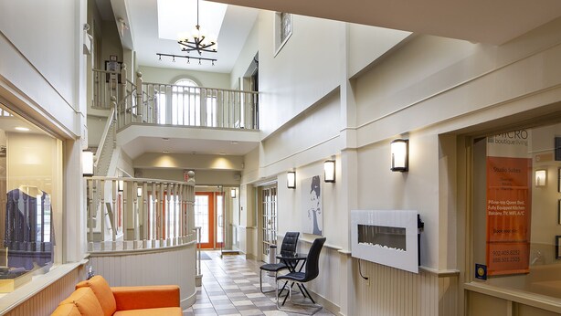 A hotel lobby with a checkered floor, a sofa, a staircase, and a signboard. - Micro Boutique Living - Antigonish (Antigonish)