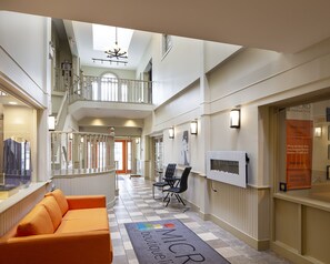 Un hall d’hôtel avec un sol à carreaux, un canapé, un escalier et un panneau indicateur.