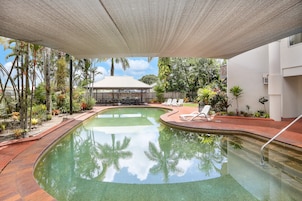 Una piscina al aire libre, sillones reclinables de piscina