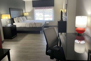 A hotel room with a bed, bedside tables, a desk, a chair, a TV, and a window with a view.