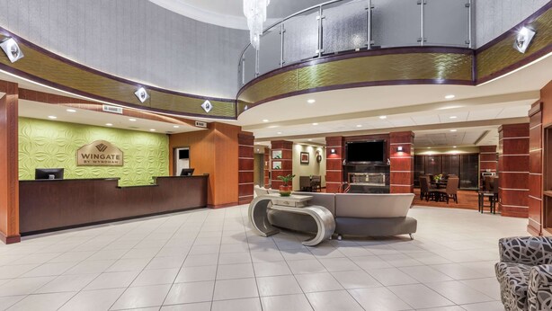 A hotel lobby with a reception desk, seating area, and a staircase. - La Quinta Inn & Suites by Wyndham Tulsa Midtown (Tulsa)
