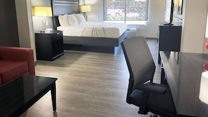 A hotel room with a bed, a desk, a chair, a TV, and a window with a view. - La Quinta Inn & Suites by Wyndham Tulsa Midtown (Tulsa)
