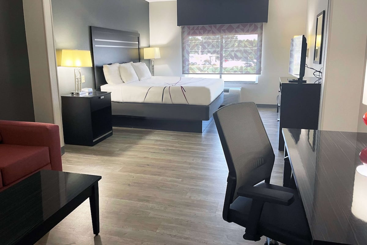 A hotel room with a bed, a desk, a chair, a TV, and a window with a view.