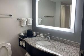 Un baño con lavamanos de encimera de granito, un espejo, toallero y un inodoro.