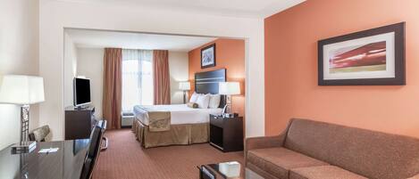 A hotel room with a bed, a sofa, a desk, and a TV.