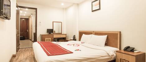 A hotel room with a wooden bed, a bedside table with a phone, a nightstand, a mirror, and a television on the wall.