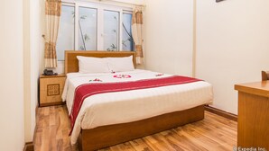 A neatly arranged bedroom with a wooden bed, a bedside table, a small desk, and a window with curtains. - Hanoi Charming House (Hanoi)