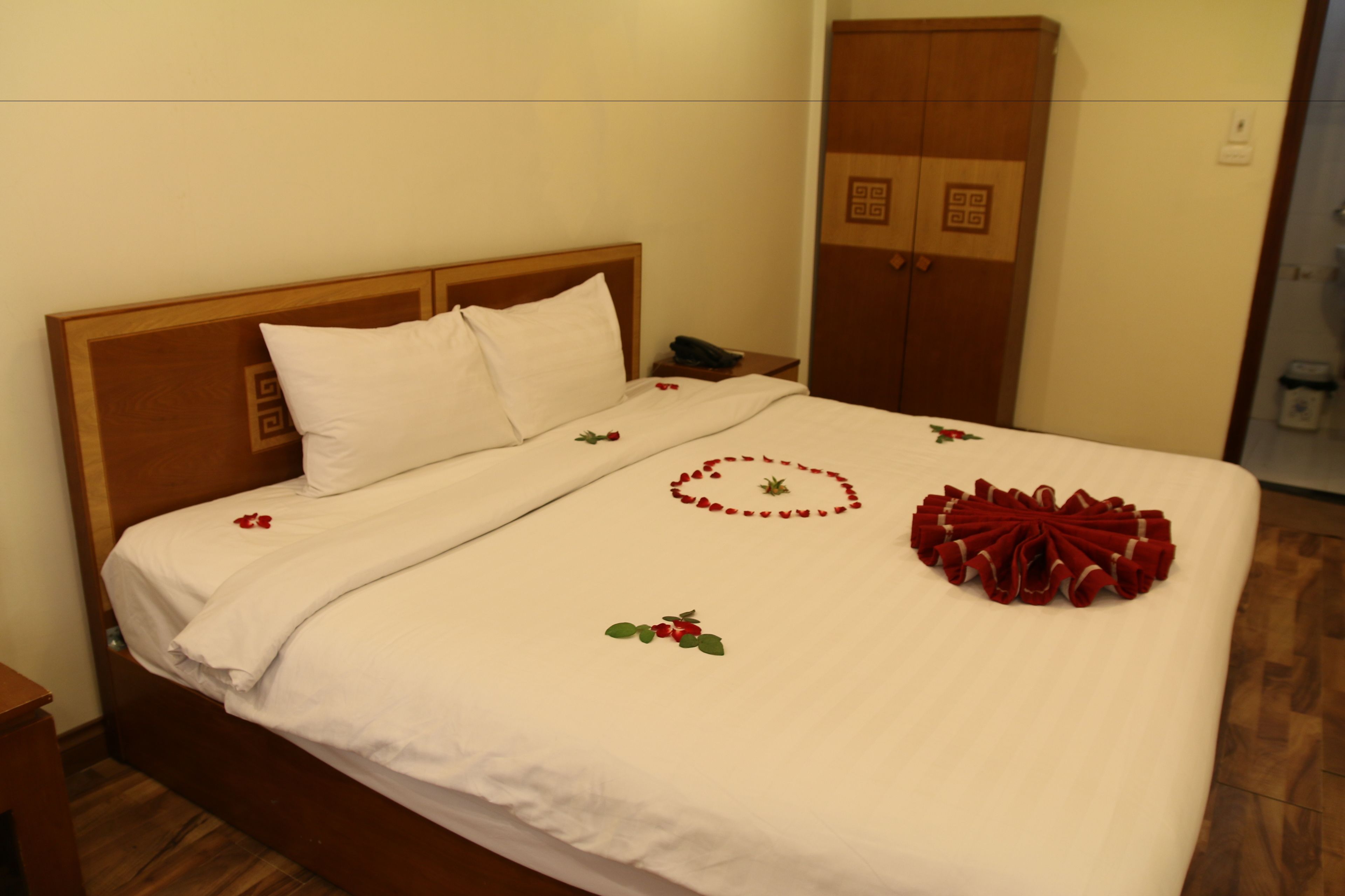 A neatly made bed with white linens and decorative floral patterns.