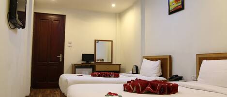 A hotel room with two beds, a wooden door, a flat-screen TV, a bedside table, a mirror, and a painting on the wall.