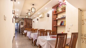 A restaurant with multiple tables and chairs, wooden decor, and a tiled wall with artwork. - Hanoi Charming House (Hanoi)