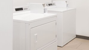 Twee witte wasmachines met voorlader in een wasserij met betegelde vloer.