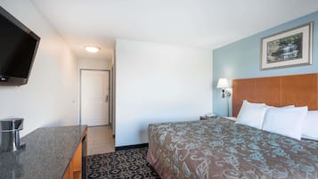 Quarto de hotel com uma cama, televisão, escrivaninha e porta.