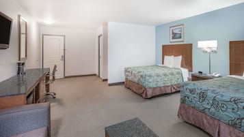 A hotel room with two beds, a desk, a chair, a TV, and a bathroom door.
