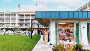 Un hotel con un área de estar al aire libre techada, piscina y un edificio de varios pisos con balcones.