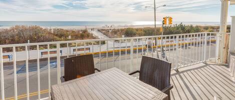 Un balcon avec vue sur la plage, une table et des chaises.