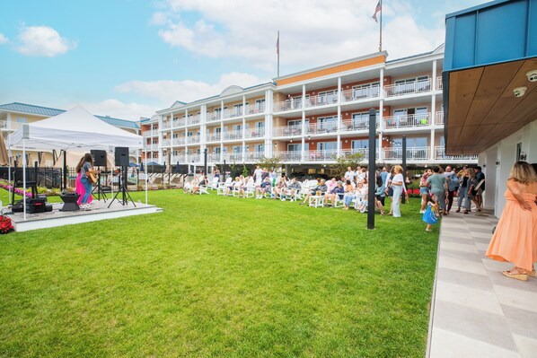 Un patio de hotel con un escenario, asientos al aire libre y un edificio de varios pisos con balcones.